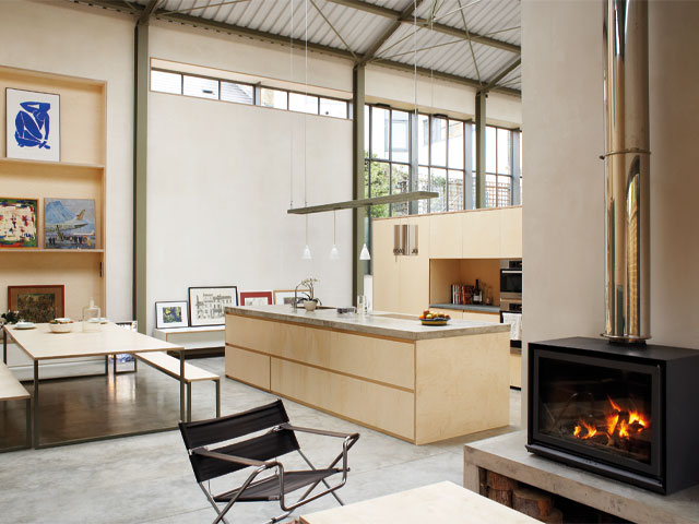Grand Designs renovations. Double height warehouse conversion wood burning fire directors chair