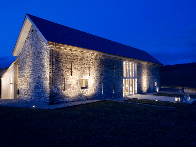 Stone barn conversion exterior at dusk up lighting