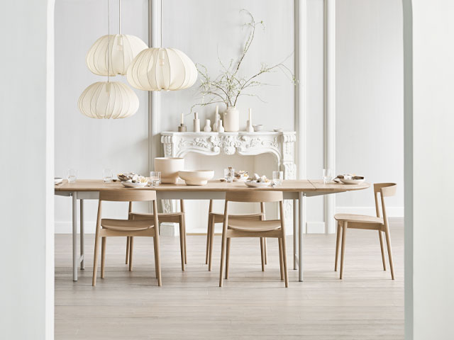 large oval dining table with scandi-style chairs in a large period dining room